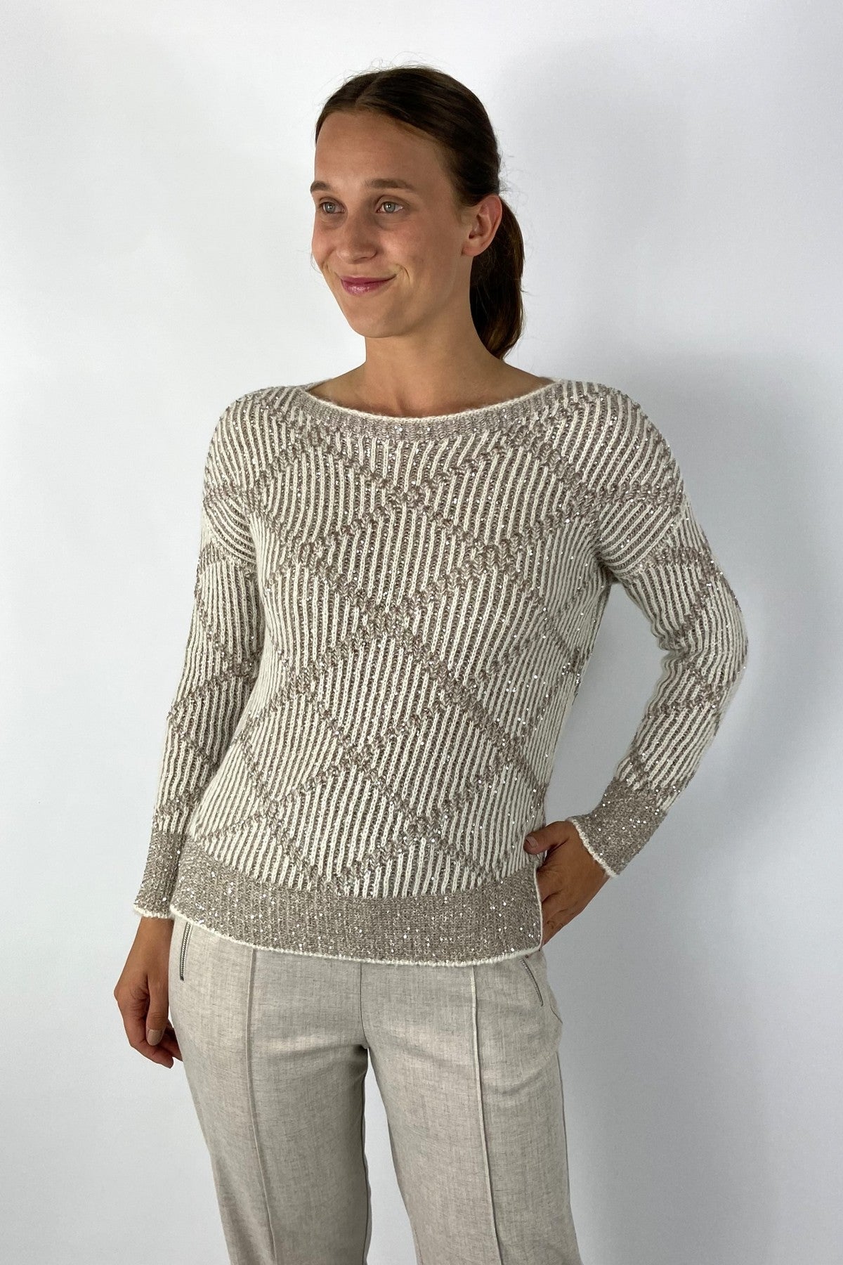 Beige gebreide pull met bicolor ruitpatroon. Het breiwerk is licht glinsterend.