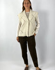 Mouwloze crèmekleurige vest in wol met lurex ruitpatroon.