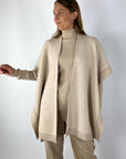 Beige capemantel in bouclé-stof voor een luxueuze uitstraling. De cape is afgeboord met ribbrei.