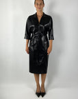De zwarte Djana-jurk van Natan in imitatieleer heeft een glanzende finish, slank silhouet en soepele rok – elegant met moderne allure.