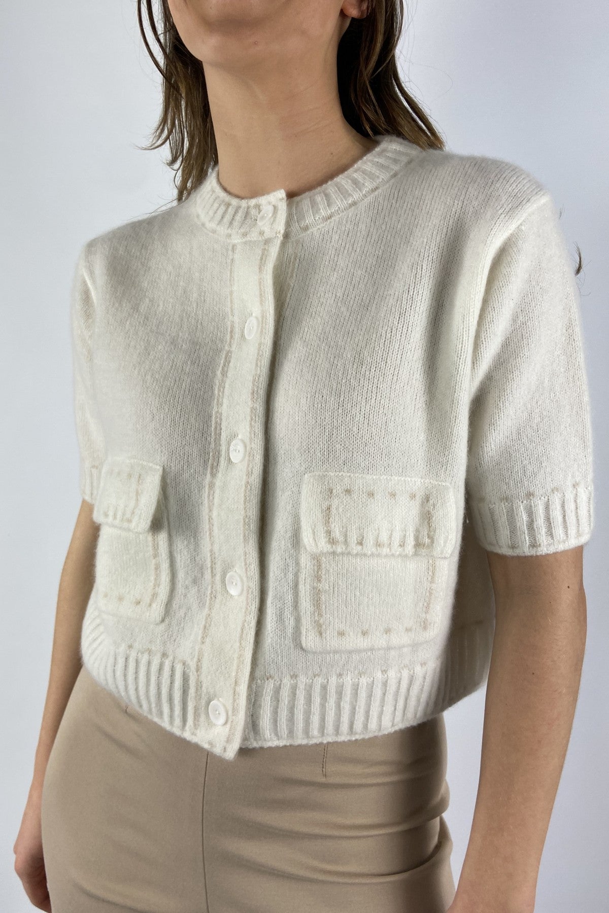261C2552BI-17: Detail van de opgestikte zakjes en beige trimming van de ecru Hemisphere cardigan.