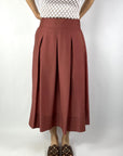 A05037 Peserico midi-rok in Photinia rood met plooien vanaf de heup en Punto Luce details op de steekzakken.