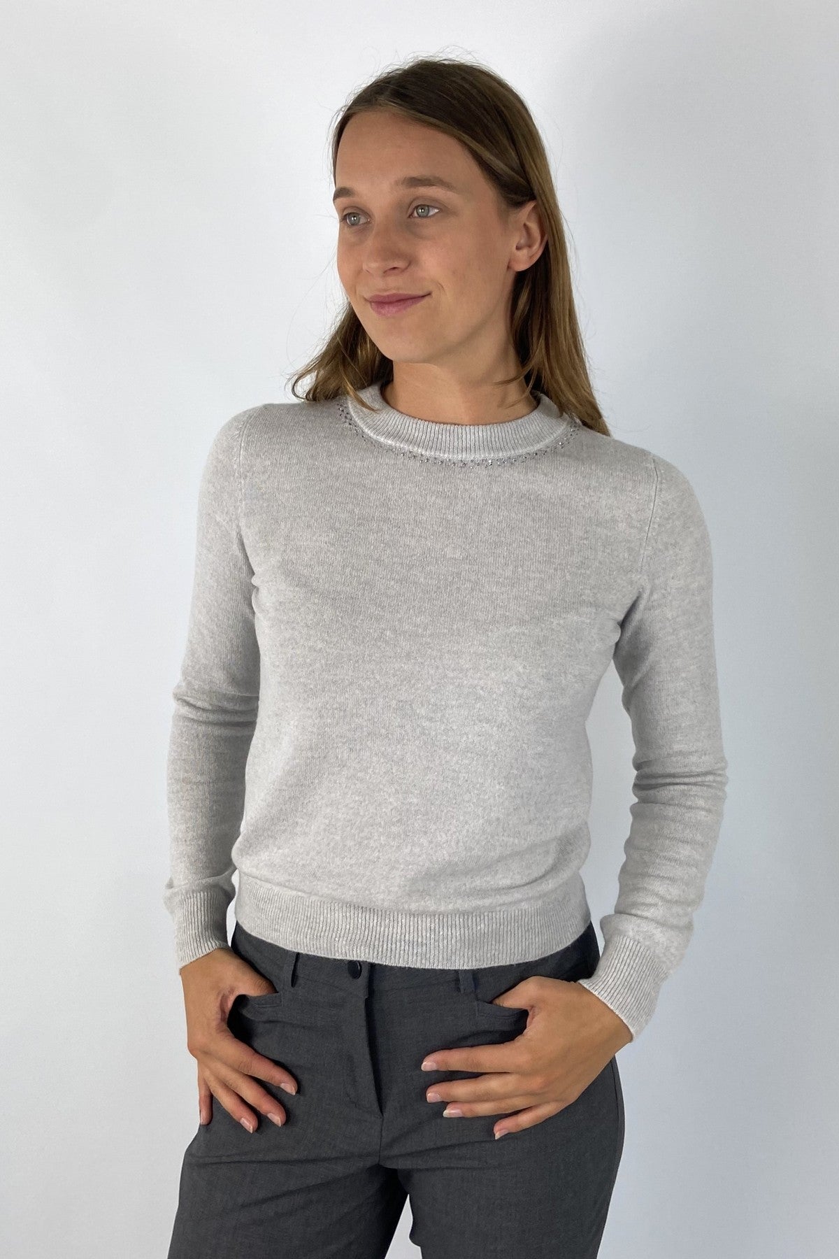 Lichtgrijs truitje in wol/cashmere in lichtgrijze tint. De ronde halsuitsnijding is voorzien van strass-details.
