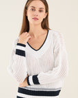 Witte Anneclaire trui met V-hals en donkerblauwe streep onderaan.