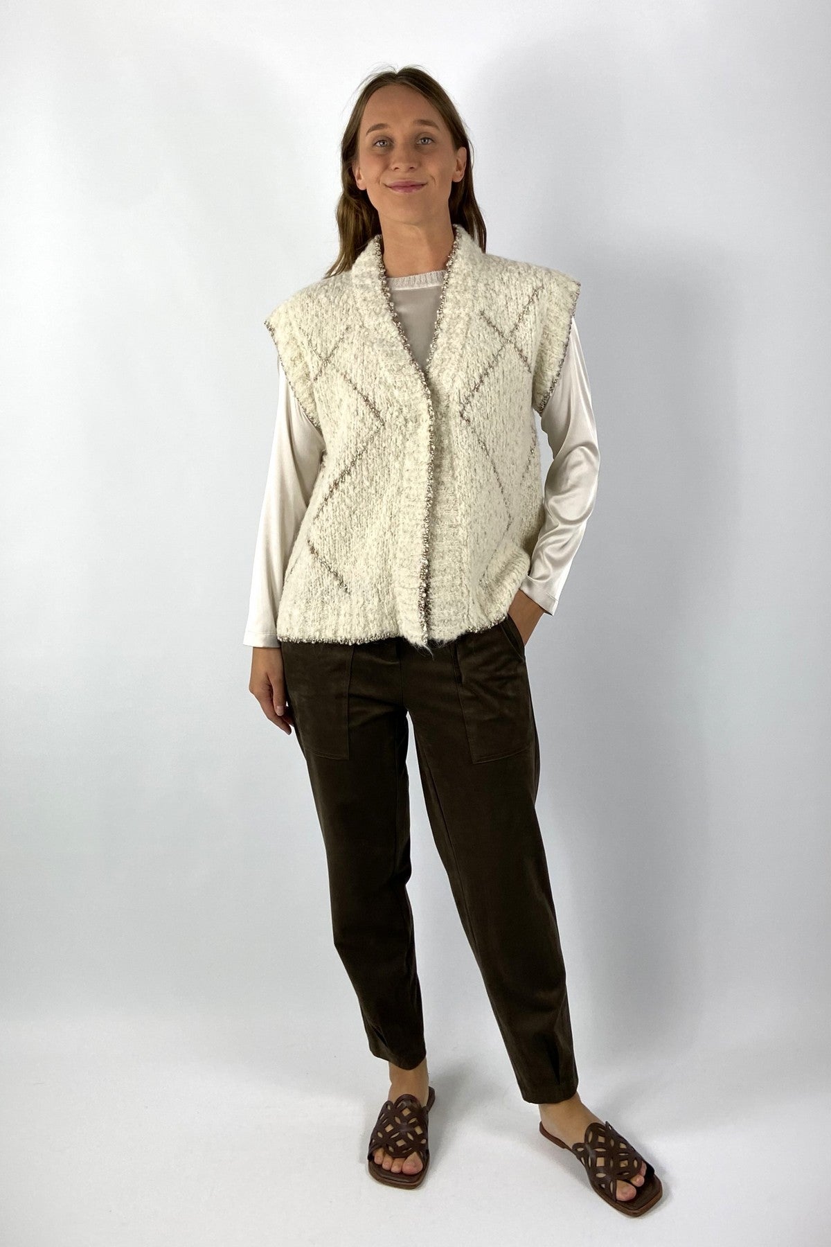 Mouwloze crèmekleurige vest in wol met lurex ruitpatroon.