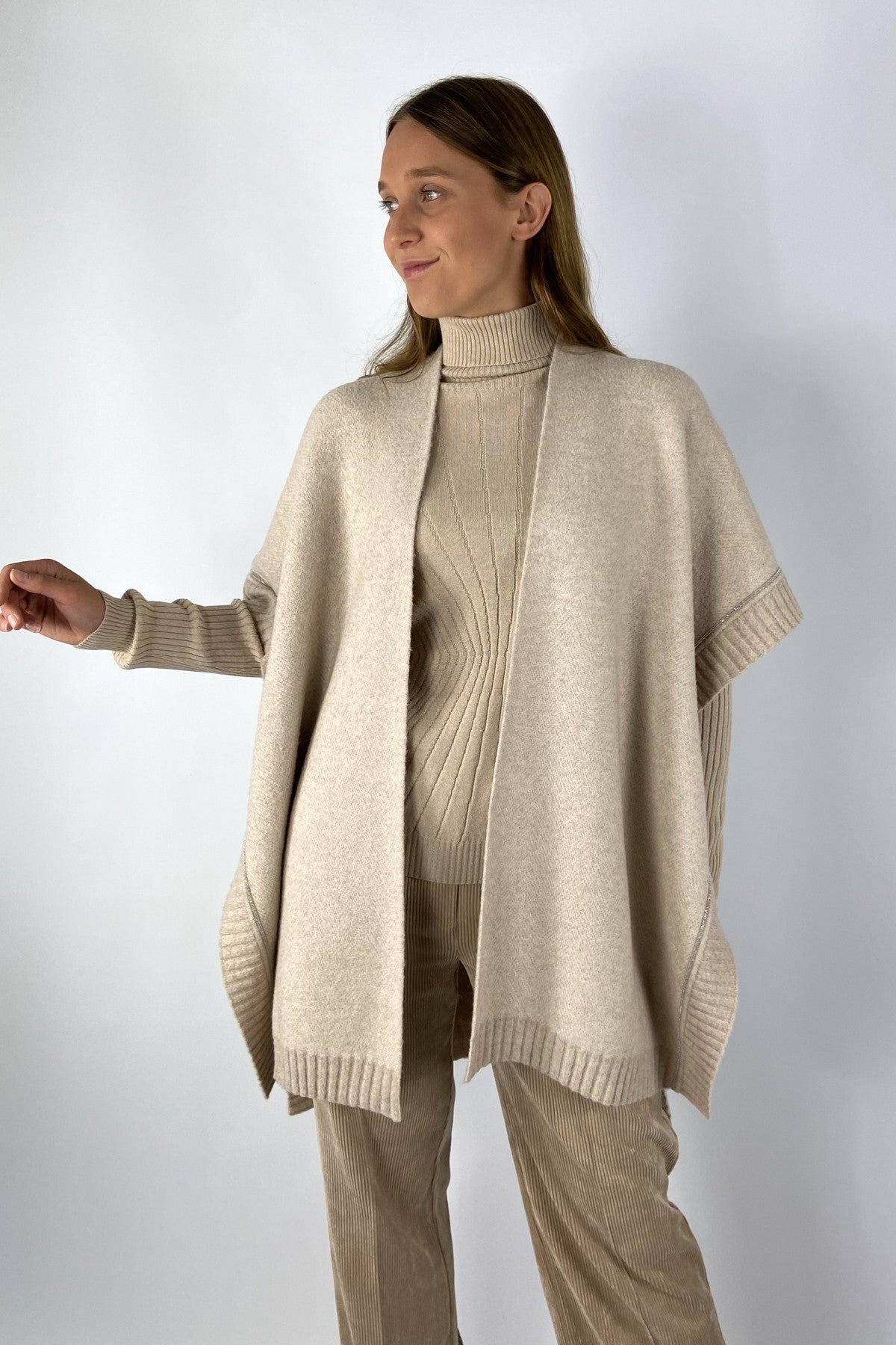 Beige capemantel in bouclé-stof voor een luxueuze uitstraling. De cape is afgeboord met ribbrei.