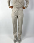 Beige broek met elastische tailleband en stropje voorzien van 2 steekzakken met rits. 