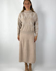 Lange rok in tweed stof. De kleur is beige-roze. Mooit te combineren met de bijpassend trui met ruit.