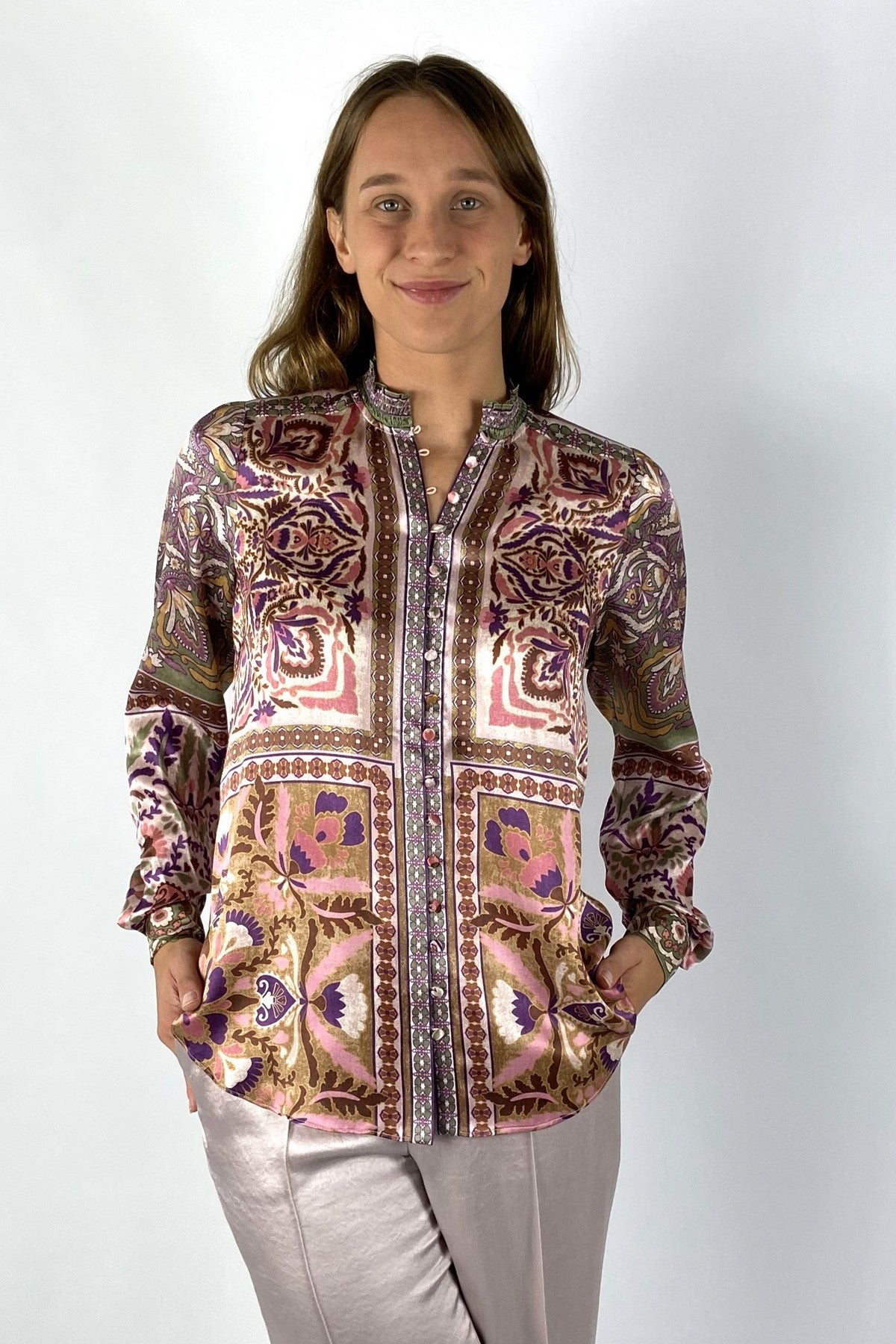 Een rechte damesblouse van zijde met print in ecru roze en burgundy. De blouse heeft een hoge hals, knoopjes vooraan en lange mouwen die verstelbaar zijn.