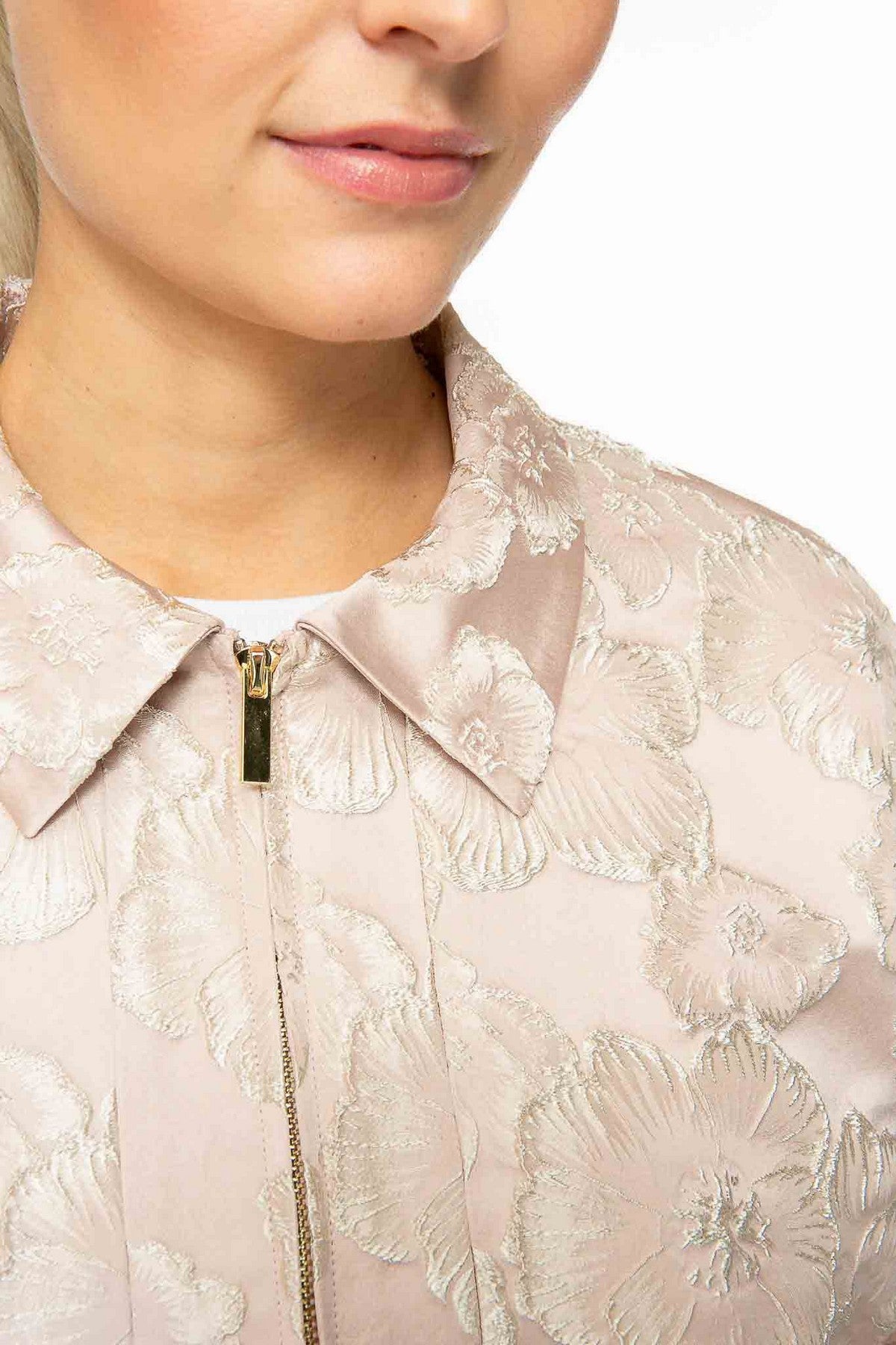 26108040: Detail van de satijn-jacquard stof en de goudkleurige metalen rits van het poederroze IVI Collection vestje.