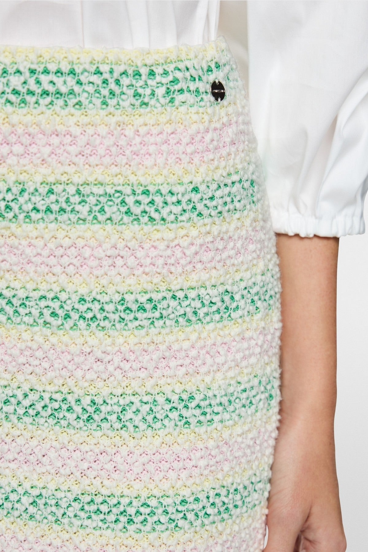 Close-up van de bouclé-structuur en het gebreide materiaal van de Marc Cain rok.