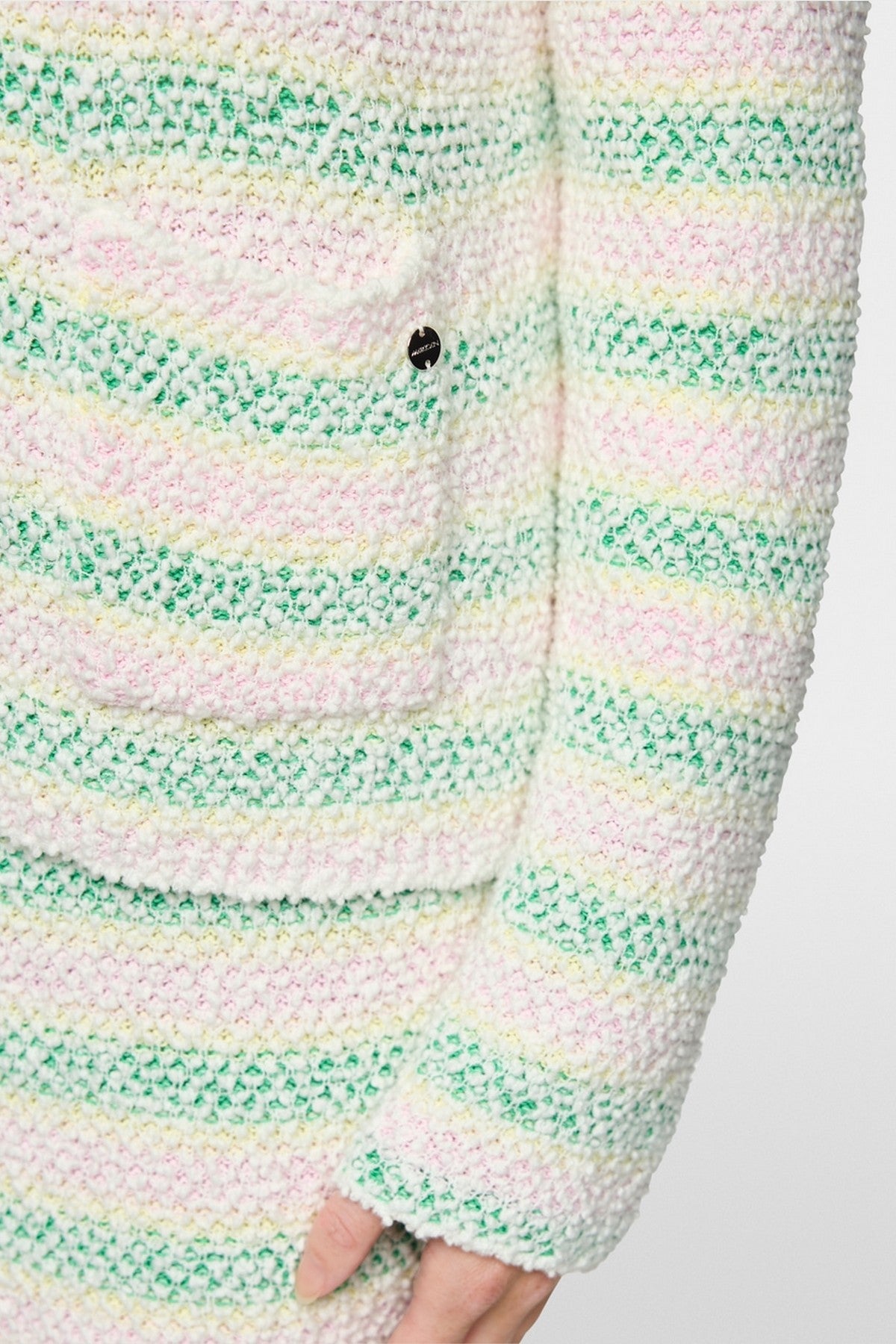 Close-up van de zachte bouclé-textuur en de opgestikte zakken van de Marc Cain cardigan AC 39.10.