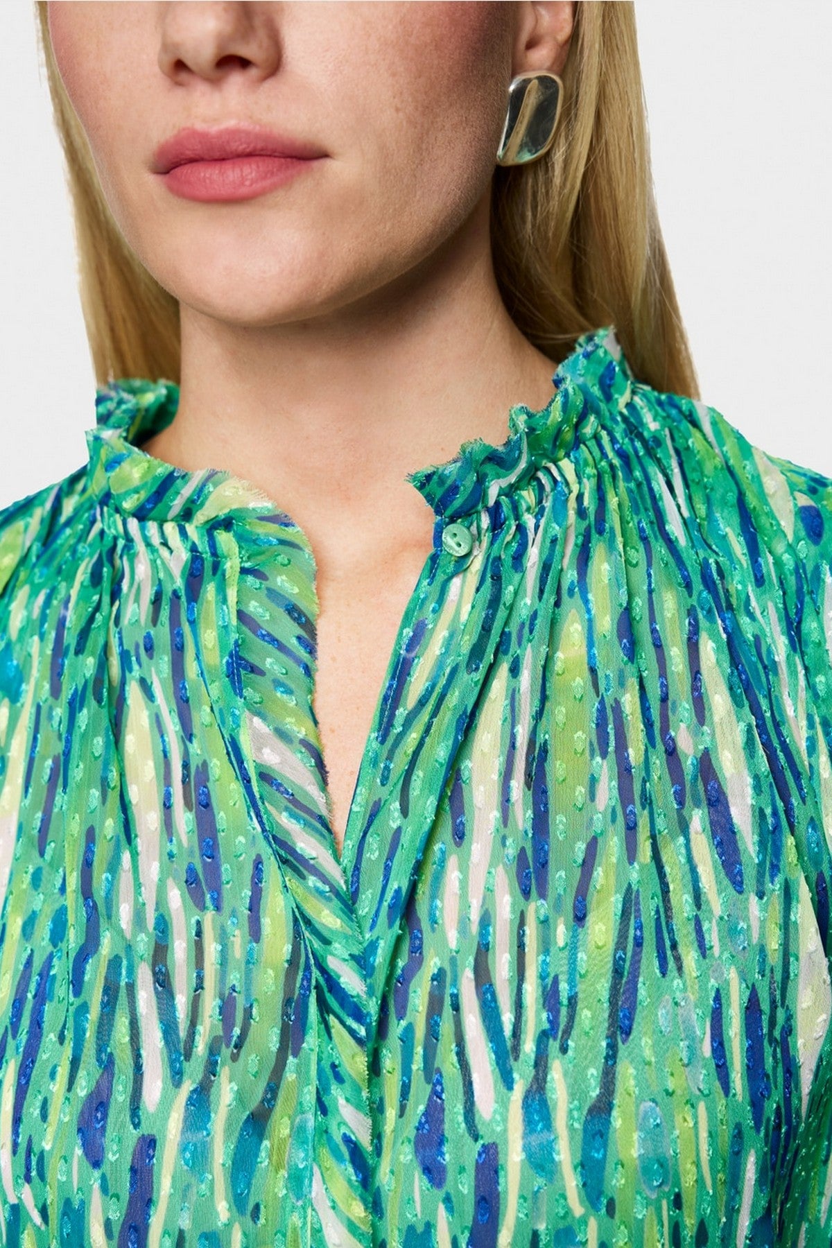 Close-up van de ruches aan de kraag en de fijne print van de Marc Cain top.