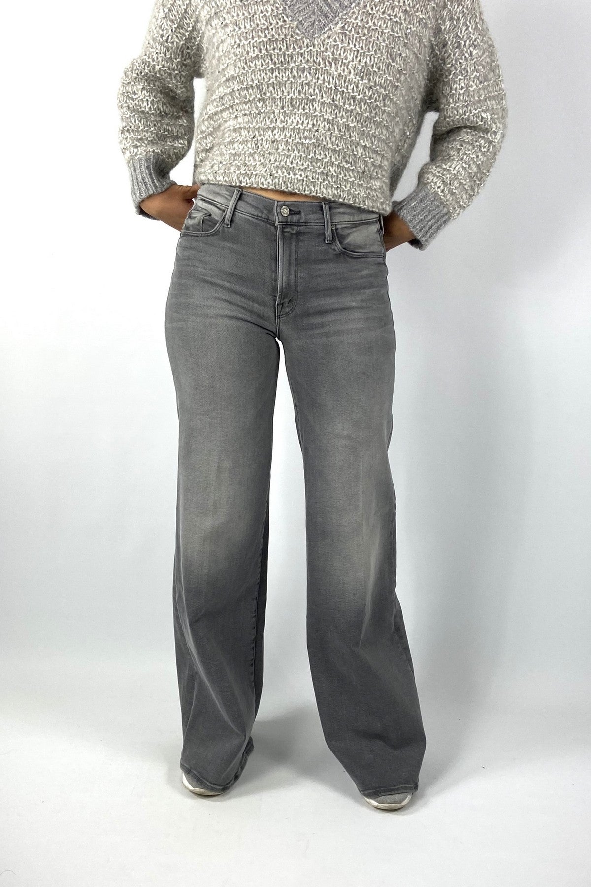 Een grijze damesjeans met middelhoge taille en wijde, recht vallende pijpen. De broek heeft voor- en achterzakken met decoratief stiksel en een witte zilveren knoopsluiting.