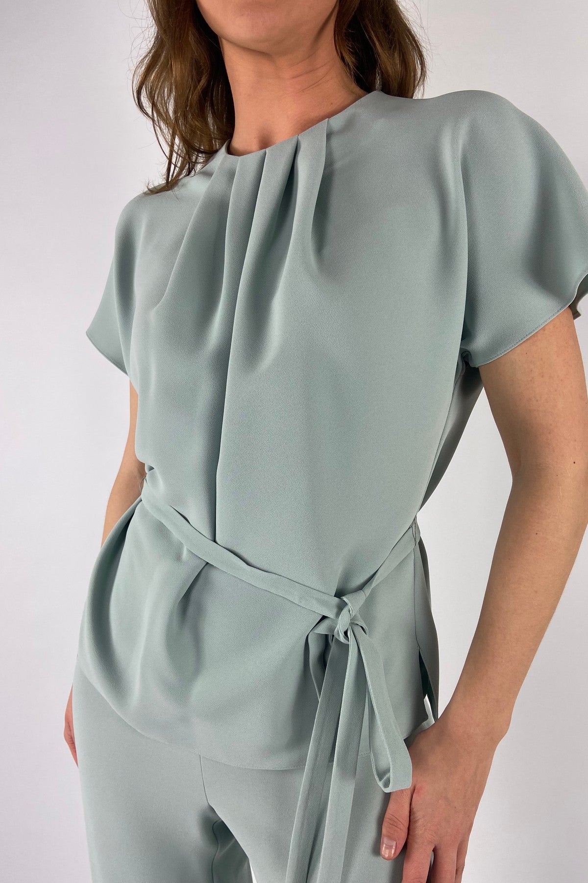 Close-up van de gesmokte halslijn en de verfijnde mintkleurige crêpestof van de Elton top van Natan.