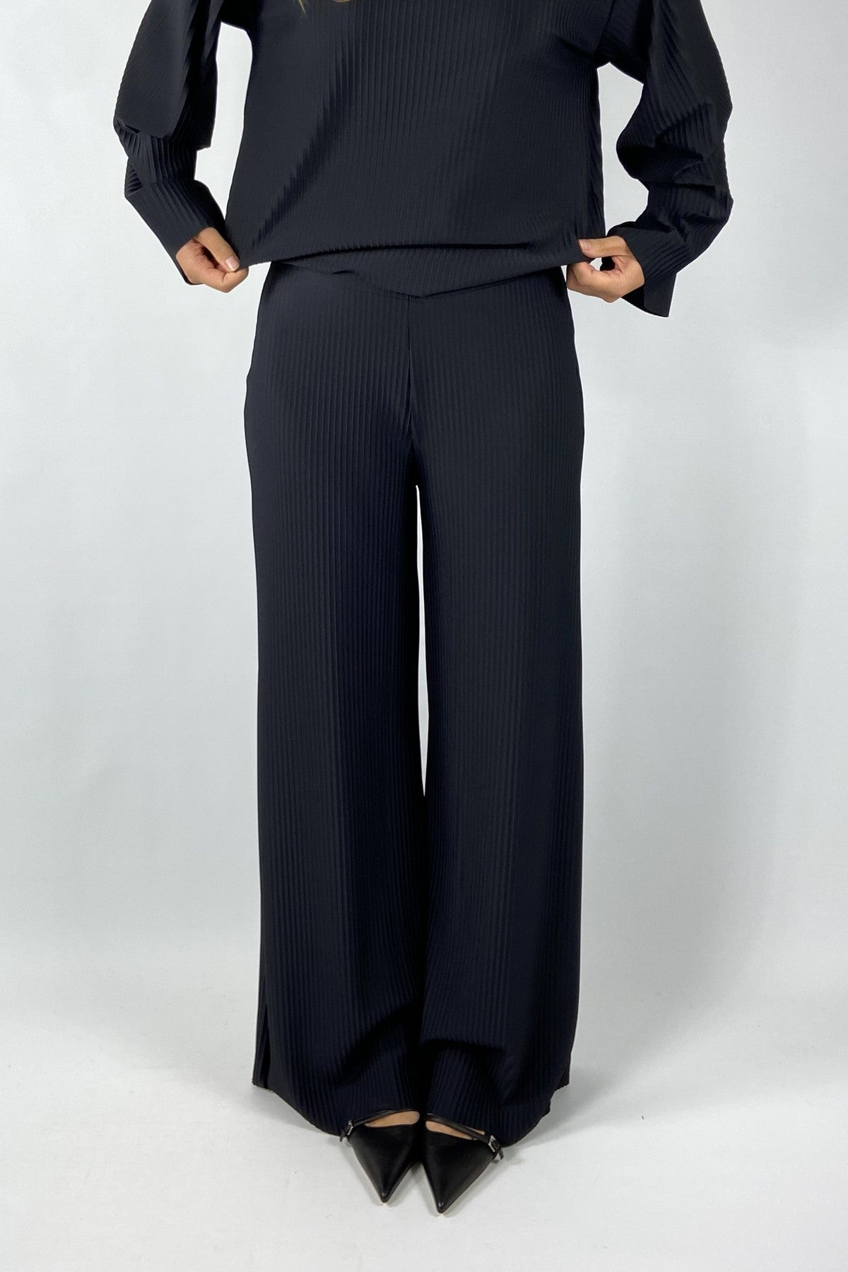 Wijde rechte broek in zwarte travelwear-stof met micro-plissé. Comfortabel én elegant, ideaal voor zowel casual als chique momenten.