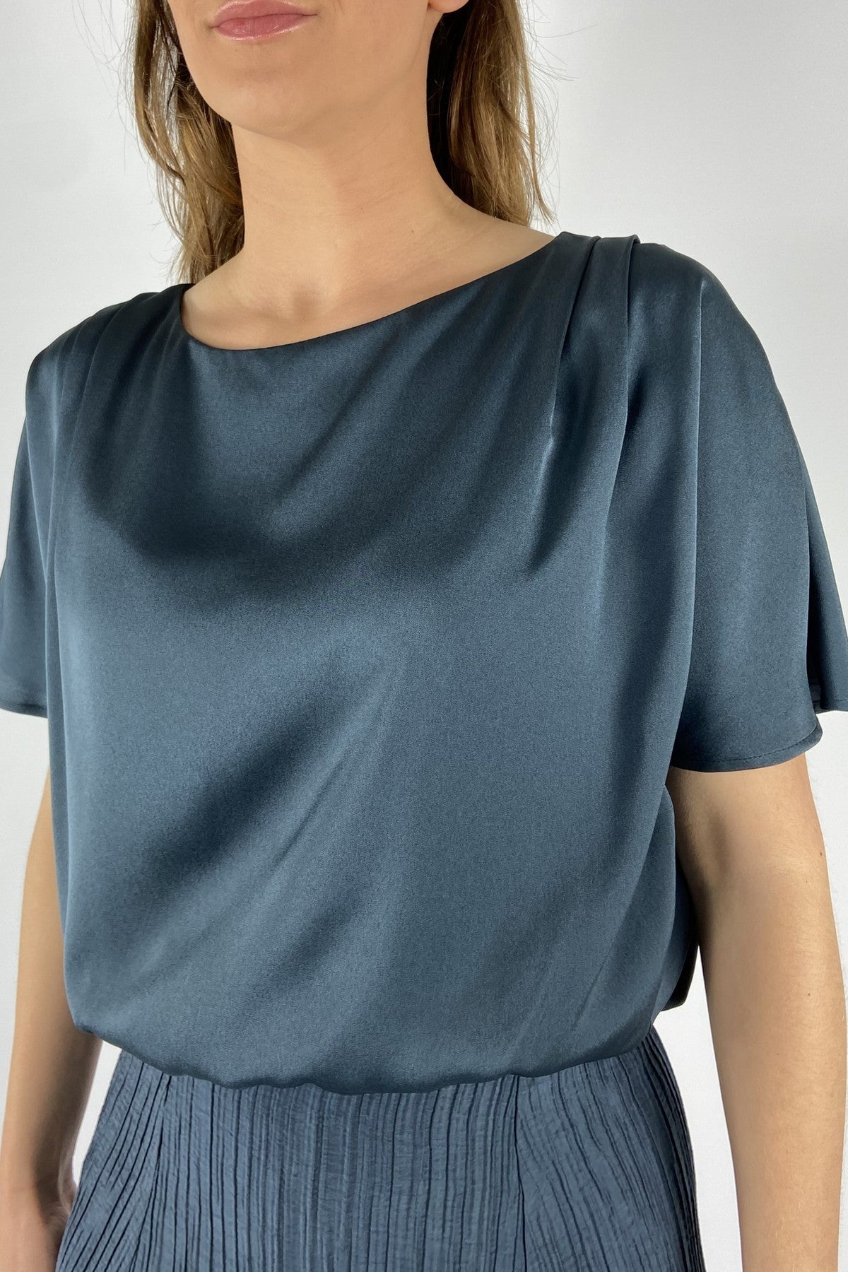 Oscar The Collection close-up van de gedrapeerde plooitjes op de schouder en de verfijnde blauwe glans van de Celeste top.