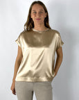 Een glanzend  amberkleurig dames-T-shirt in zijde satijn met korte, wijde kimonomouwen. Aan de halslijn schittert een subtiel glinsterend detail. De snit is losjes met een licht uitlopende zoom.